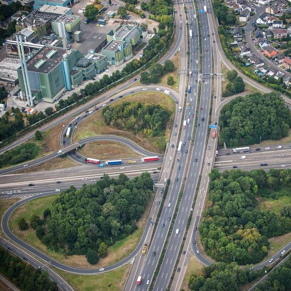 Eine Luftaufnahme zeigt das kleeblattförmige Autobahnkreuz Leverkusen. Autos und Lkw fahren über die A1 und A3.