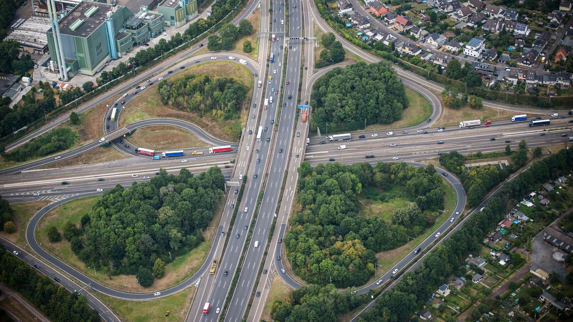Eine Luftaufnahme zeigt das kleeblattförmige Autobahnkreuz Leverkusen. Autos und Lkw fahren über die A1 und A3.