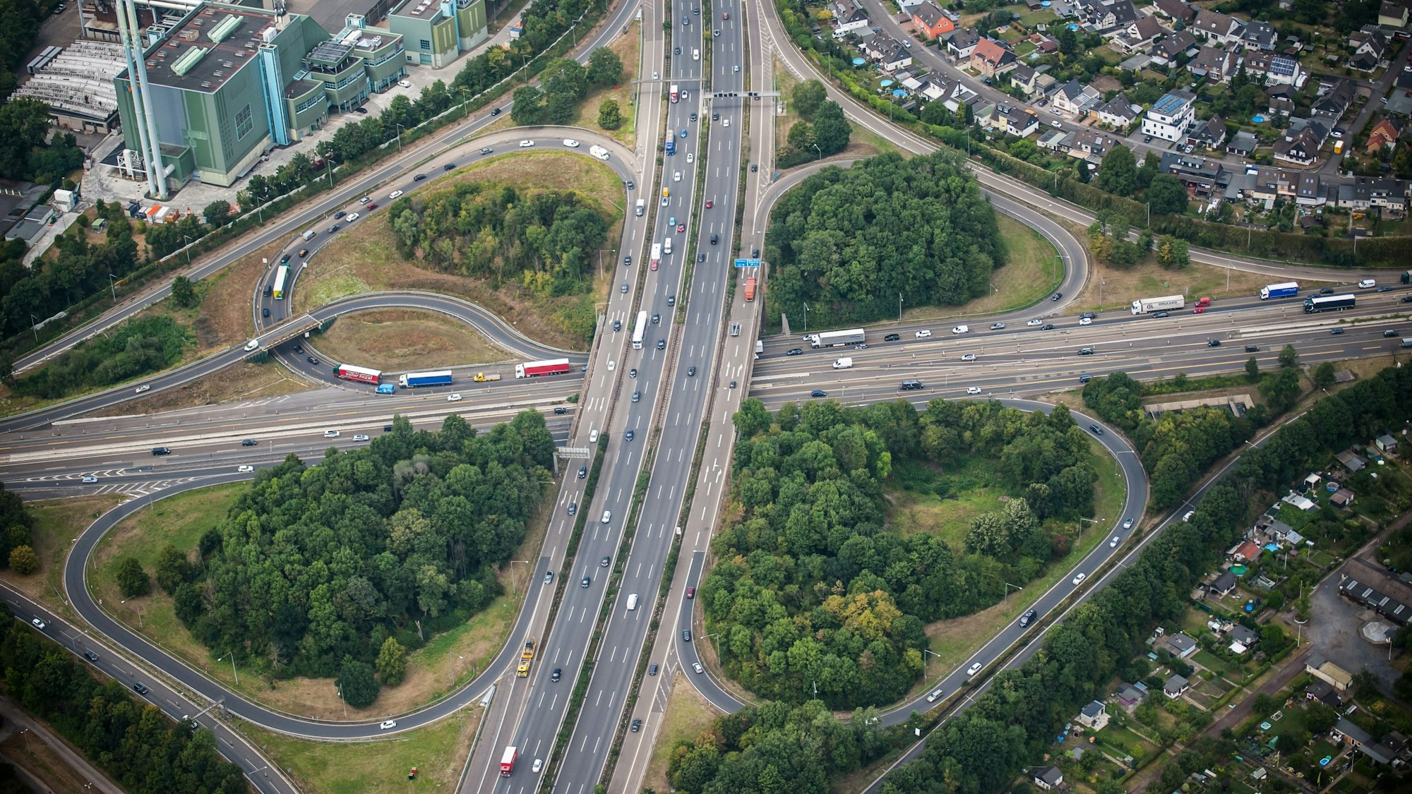 Eine Luftaufnahme zeigt das kleeblattförmige Autobahnkreuz Leverkusen. Autos und Lkw fahren über die A1 und A3.