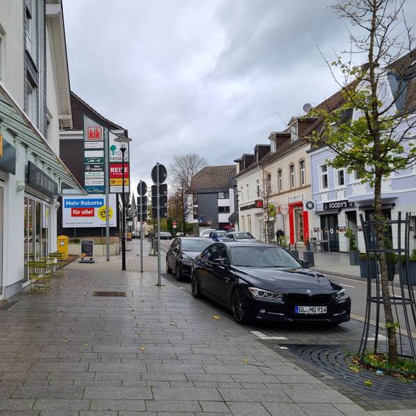 Innenstadt Burscheid, Hauptstraße mit Bäckerei und Auto.