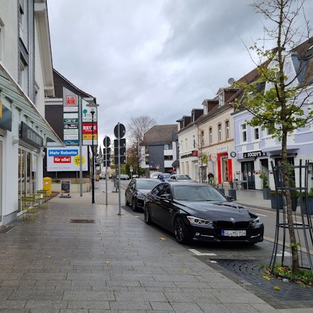 Innenstadt Burscheid, Hauptstraße mit Bäckerei und Auto.