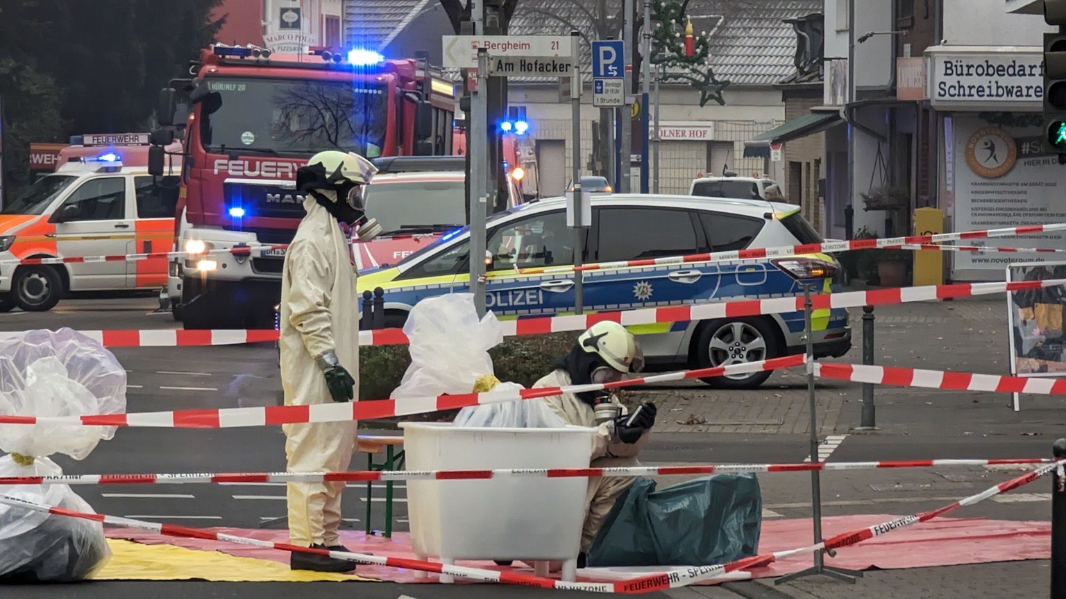 Sondereinsatzkräfte der Feuerwehr arbeiten in kompletter Ausrüstung in einem abgesperrten Bereich.