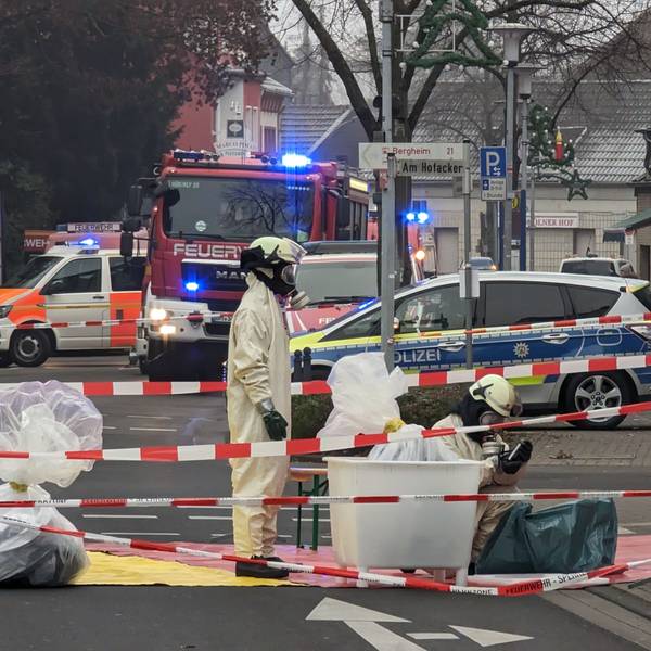 Sondereinsatzkräfte der Feuerwehr arbeiten in kompletter Ausrüstung in einem abgesperrten Bereich.