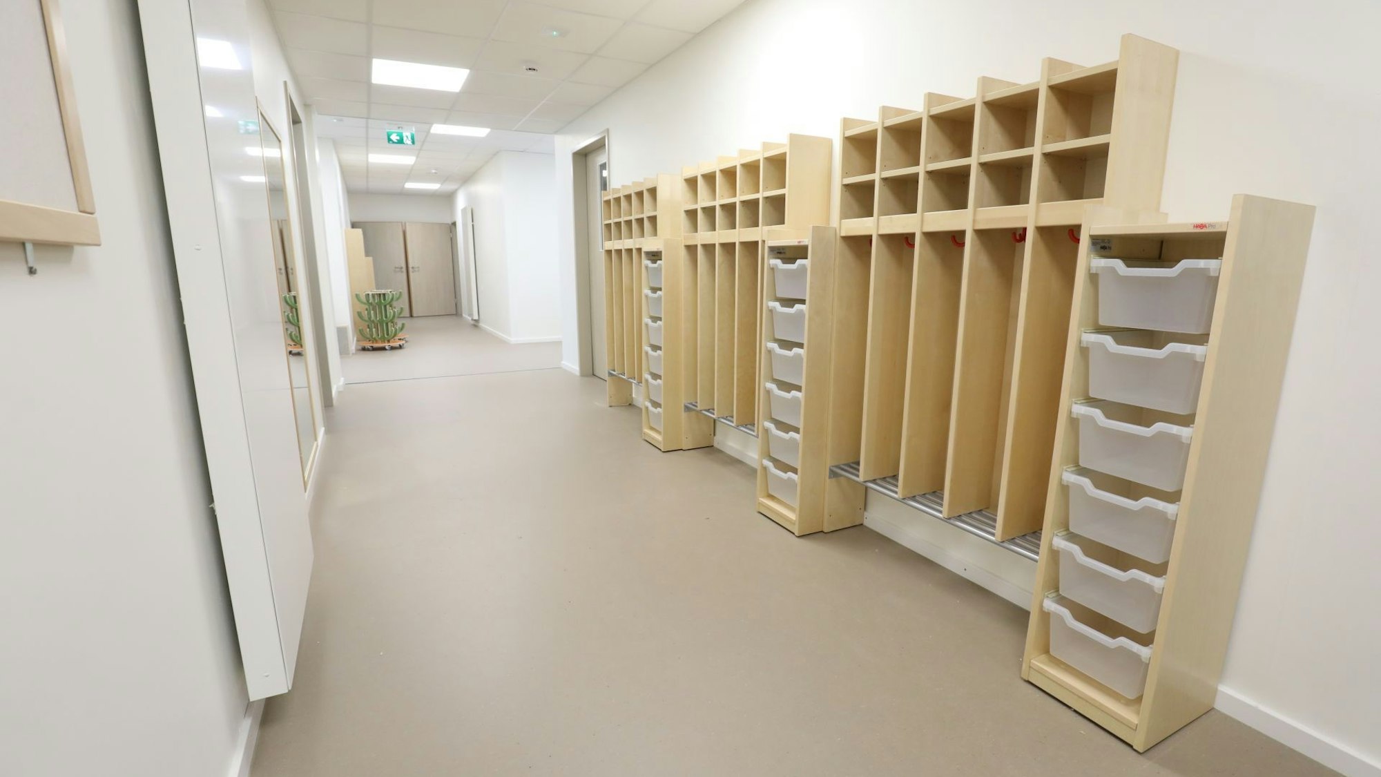 In einem langgezogenen Flur stehen auf der rechten Seite helle Holzmöbel mit kleinen Fächern für die Kleidung der Kindergartenkinder. Noch sind sie leer.