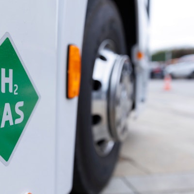 Auf einem weißen Lkw klebt ein grüner viereckiger Aufkleber, auf dem H2 Gas steht.