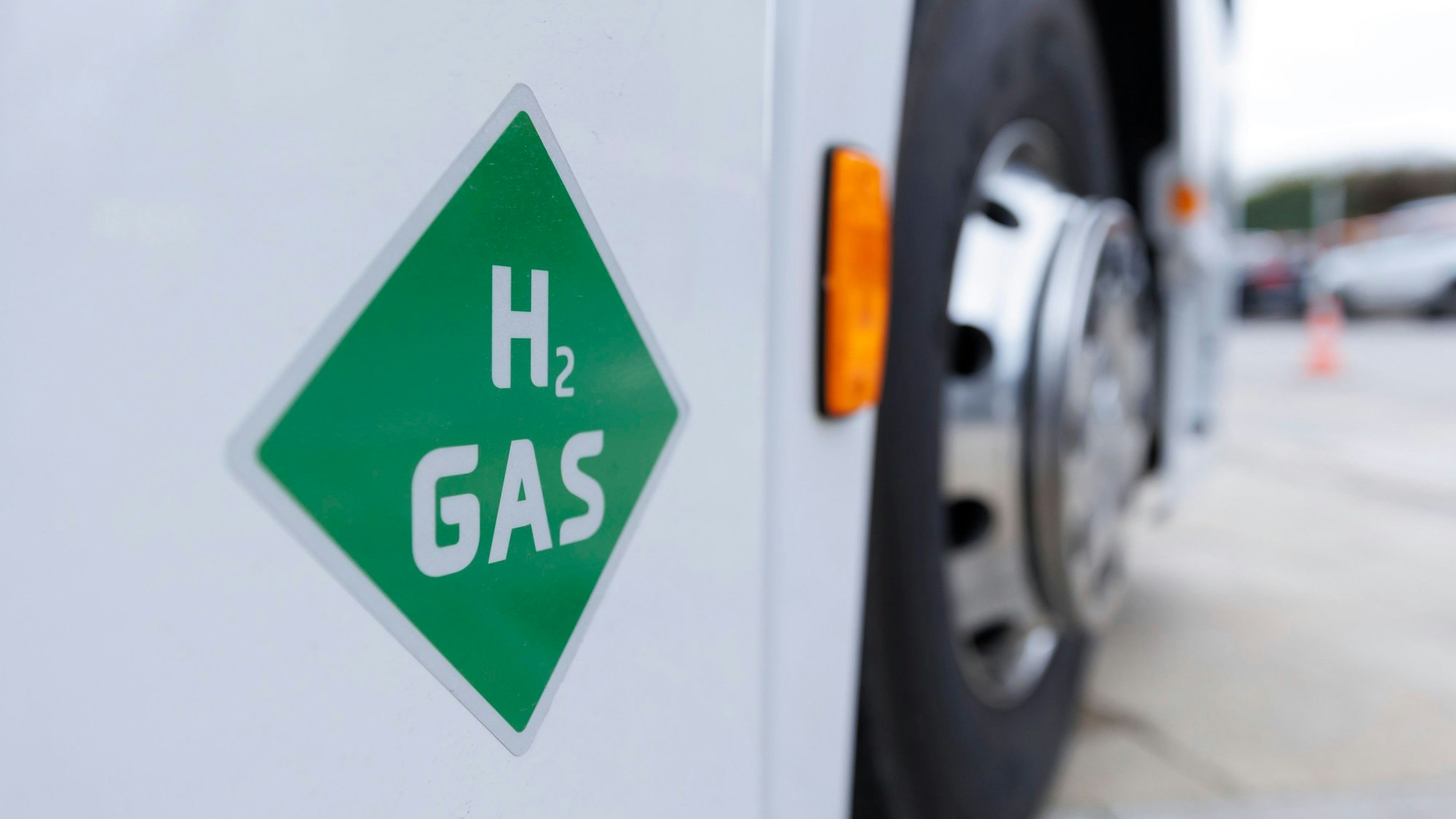 Auf einem weißen Lkw klebt ein grüner viereckiger Aufkleber, auf dem H2 Gas steht.