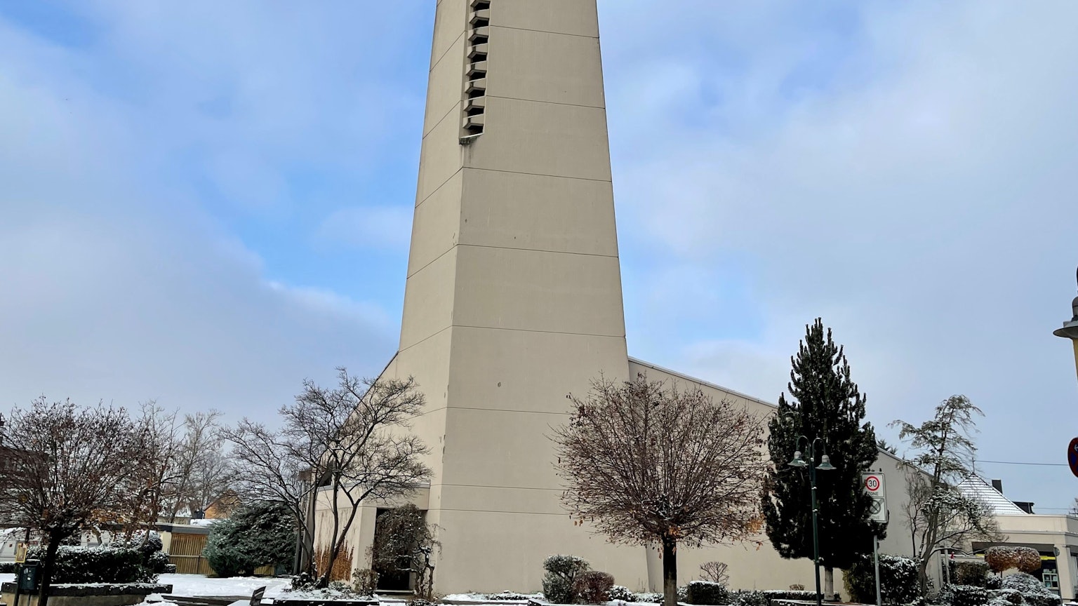 Der Kirchturm der Pfarrgemeinde St. Anna in Sankt Augustin vor blauem Himmel mit weißen Wolken