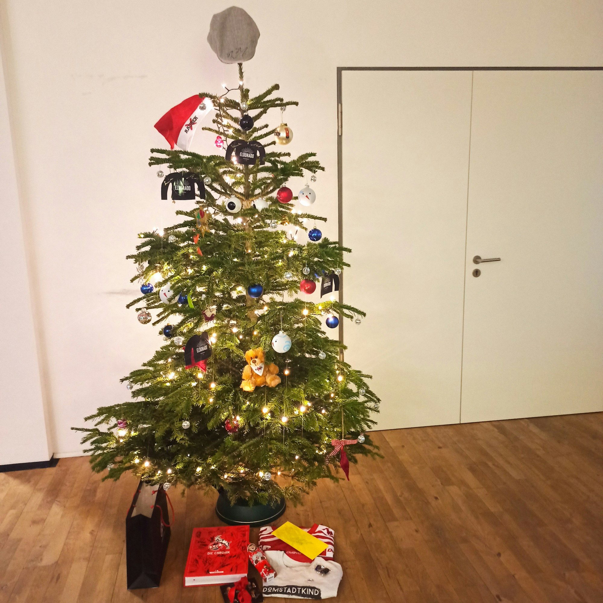 Der geschmückter Weihnachtsbaum mit der Schiebermütze auf der Spitze.