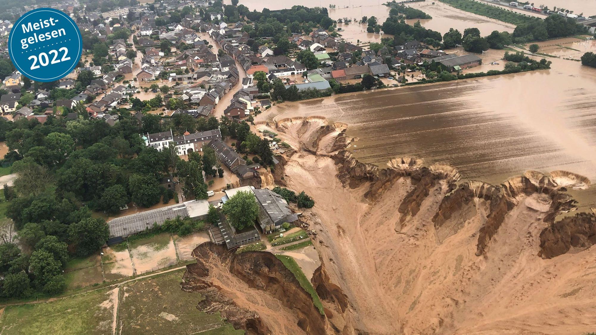 Das Wasser steht in Erftstadt-Blessem in den Straßen. Schlamm fließt an der Abbruchkante der Kiesgrube runter.