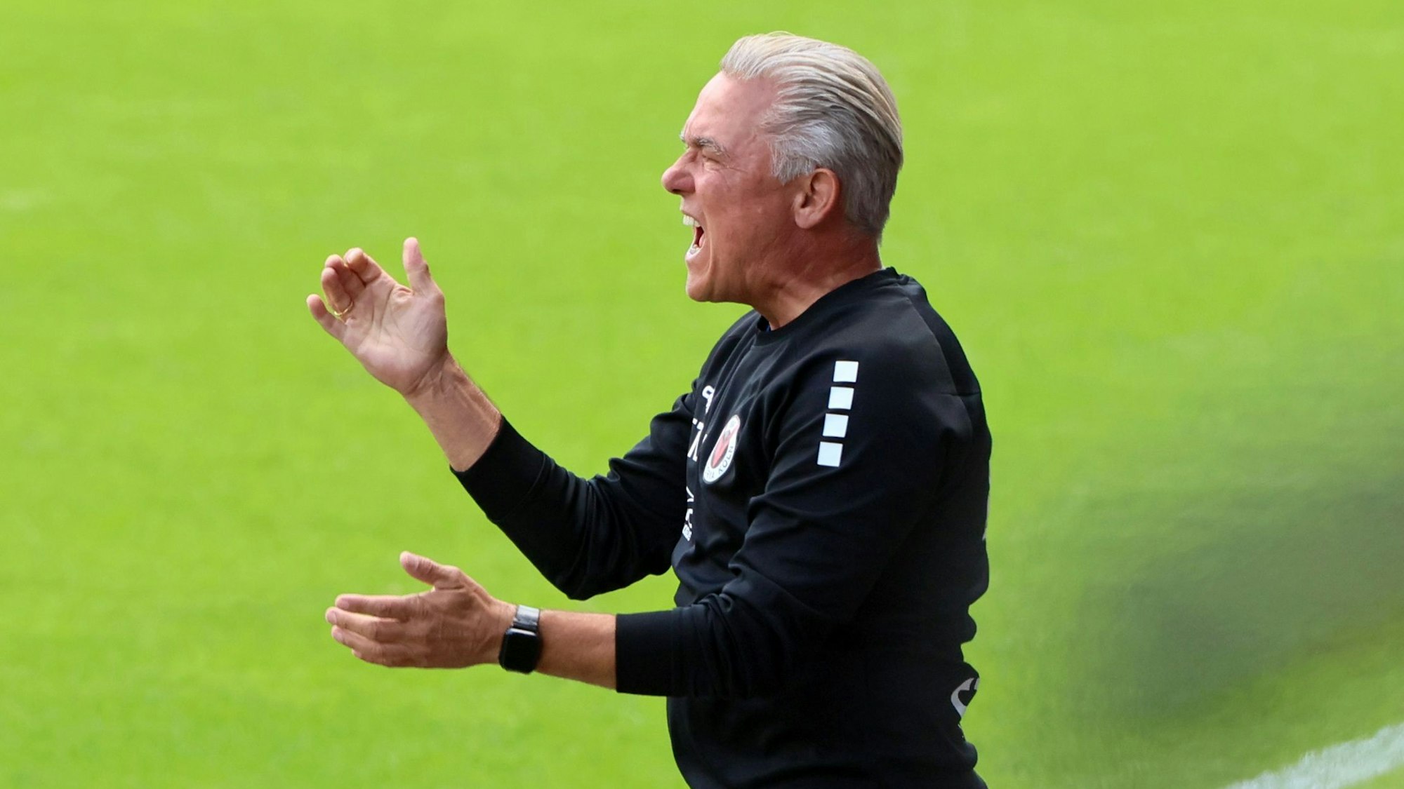 Ein Fußballtrainer steht an der Seitenlinie und feuert sein Team an.