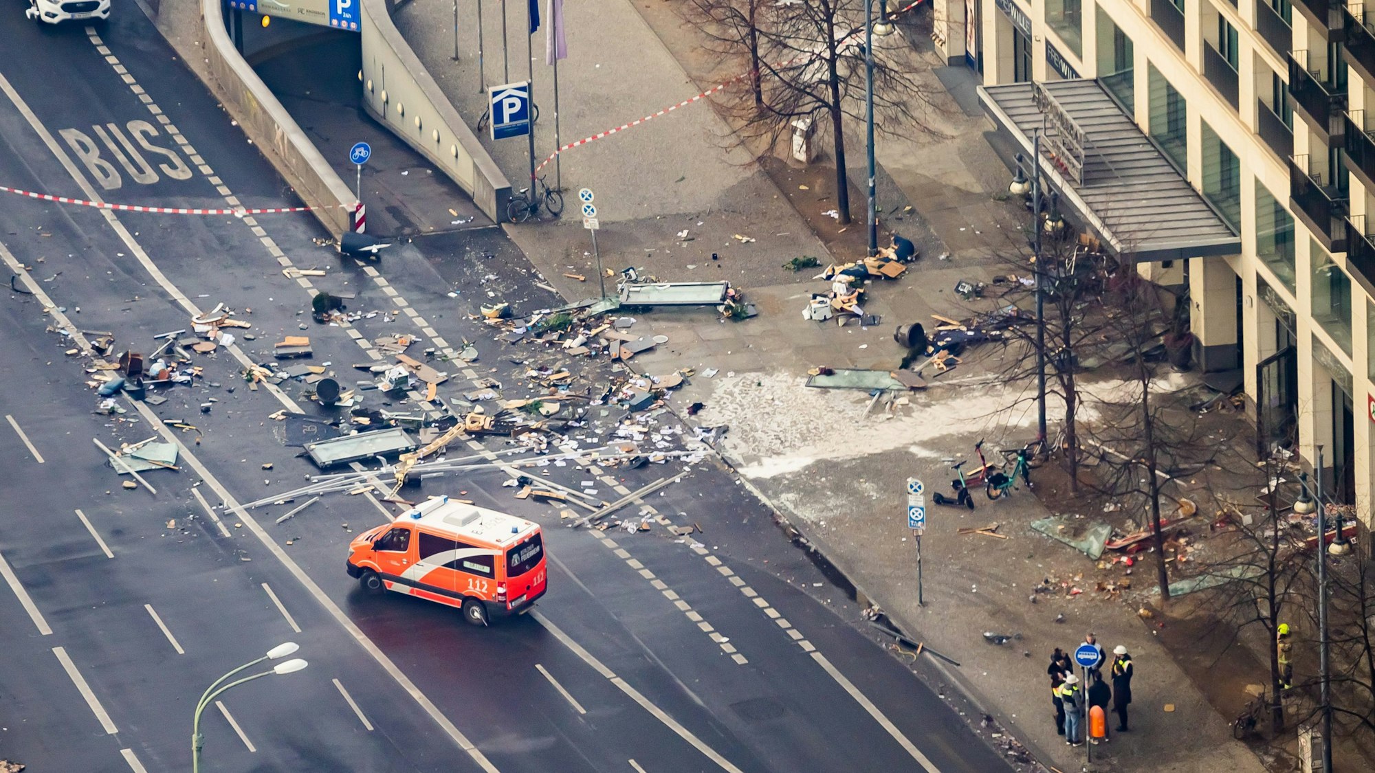 Trümmer liegen auf der Karl-Liebknecht-Straße vor einem Hotel. Ein Rettungsfahrzeug steht auf der abgesperrten Straße.