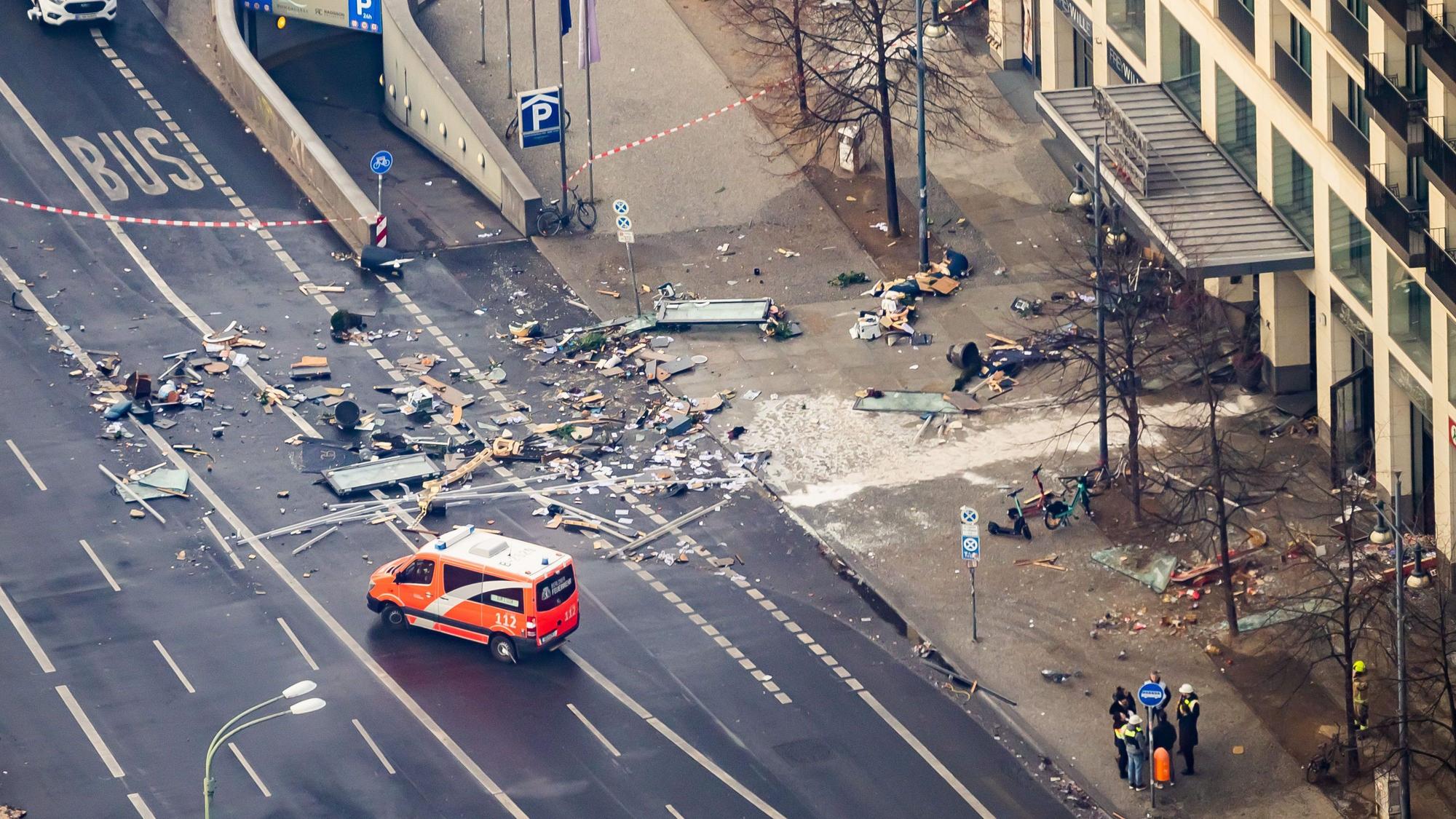 Trümmer liegen auf der Karl-Liebknecht-Straße vor einem Hotel. Ein Rettungsfahrzeug steht auf der abgesperrten Straße.