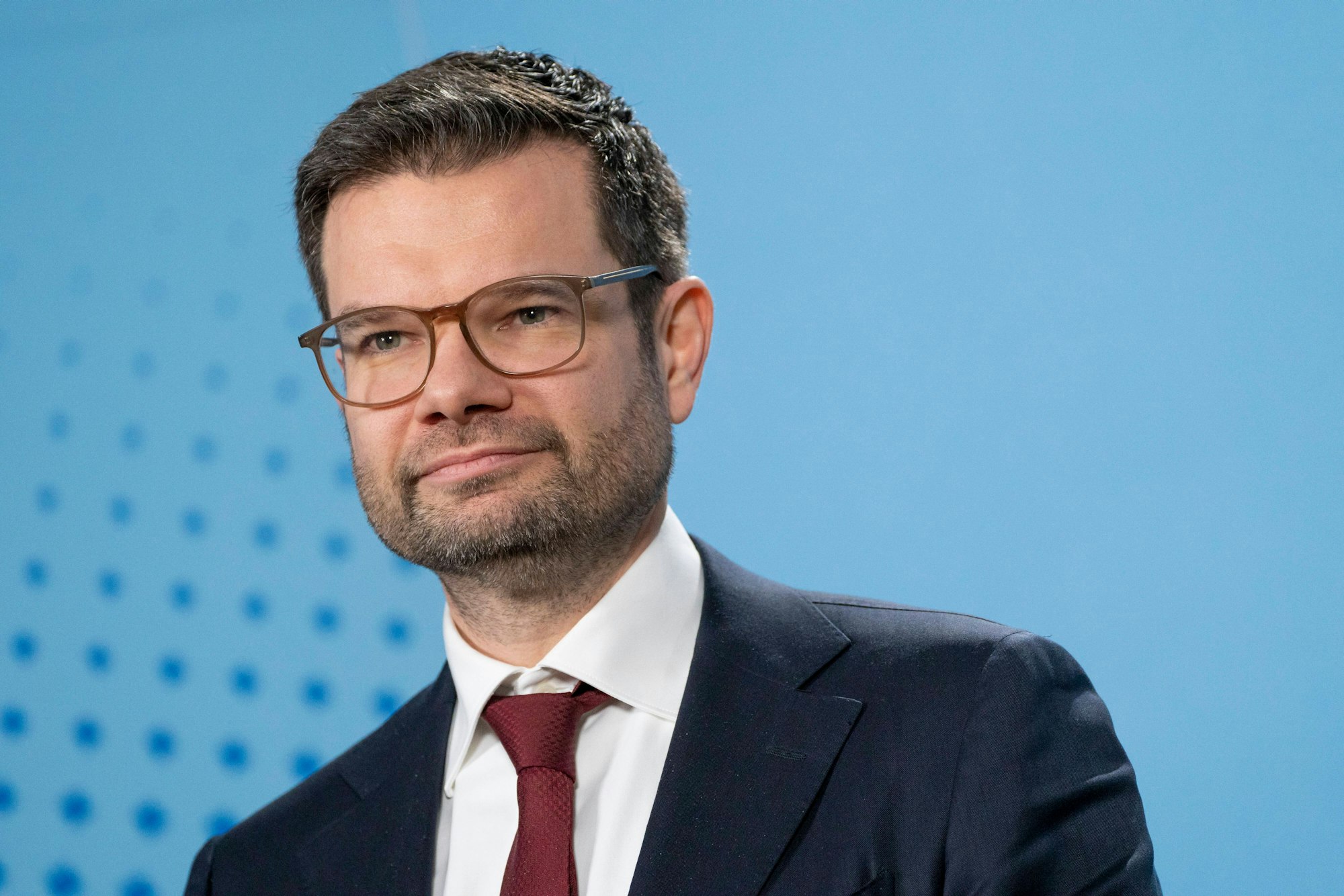 Bundesjustizminister Marco Buschmann steht vor einem blauen Hintergrund.