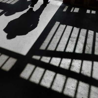 Es sind der Schatten von einem Mensch und von Gitterstäben zu sehen.