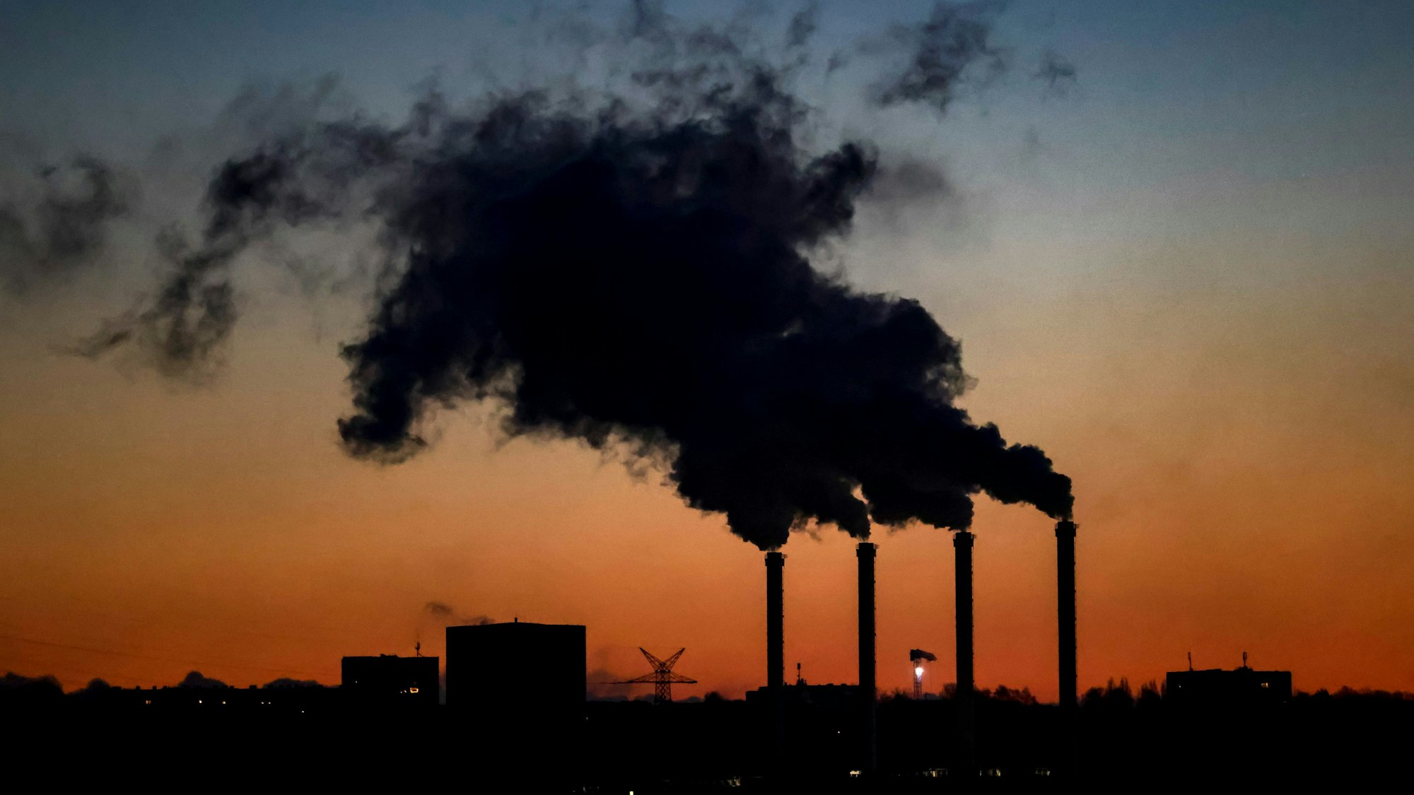 Die Schornsteine des Kieler Kraftwerks qualmen bei Sonnenaufgang im Dezember 2022.