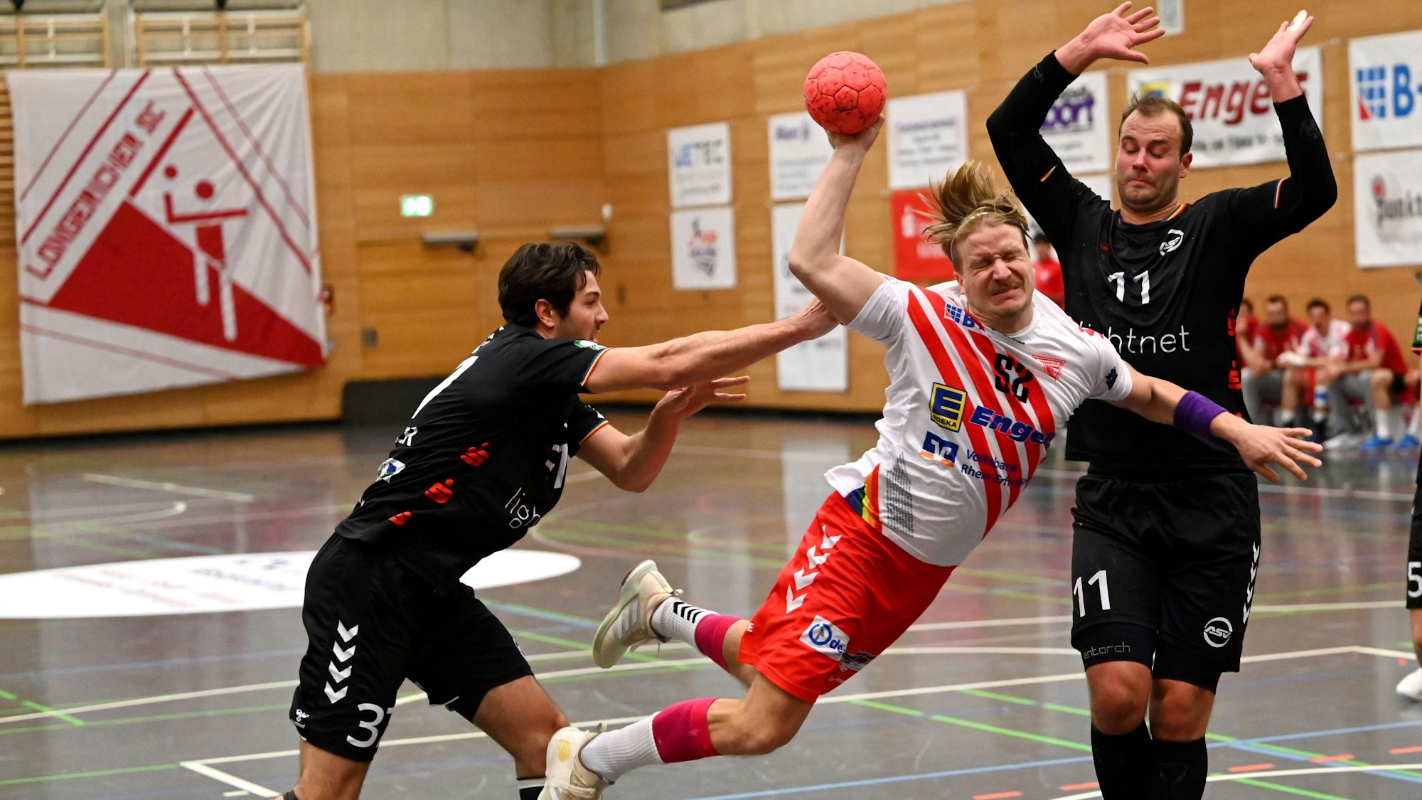 Ein Handballer setzt sich gegen zwei Gegenspieler durch und kommt zum Wurf.