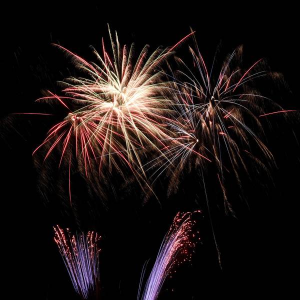 Silvesterraketen hinterlassen sternförmigen Funkenregen an einem Nachthimmel.
