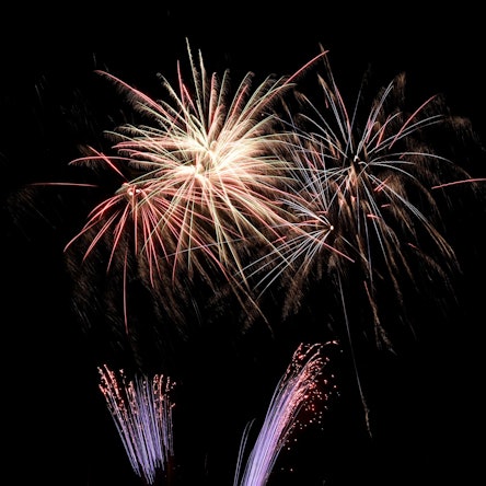 Silvesterraketen hinterlassen sternförmigen Funkenregen an einem Nachthimmel.