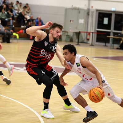 Ein Basketballer dribbelt an seinem Gegenspieler vorbei.