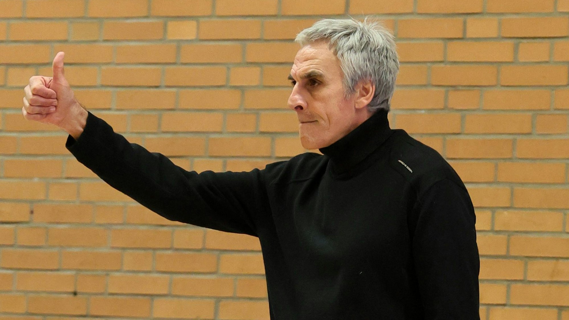 Ein Basketballtrainer hebt zufrieden den Daumen.
