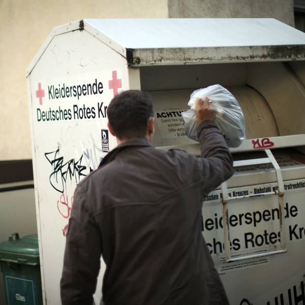 Ein Mann wirft Altkleider in einen Sammelcontainer.