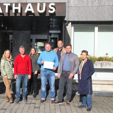 Bürgerinnen und Bürger von Blankenheim stehen mit dem Anmeldebogen des Bürgerbescheides vor dem Rathaus.