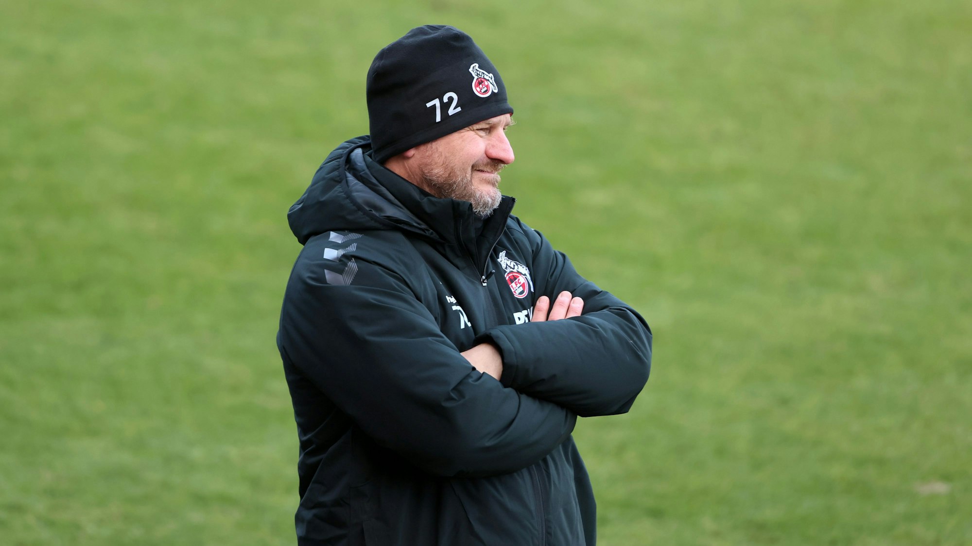 Steffen Baumgart bei einem 1. FC Köln Spiel. Er hat die Arme verschränkt.