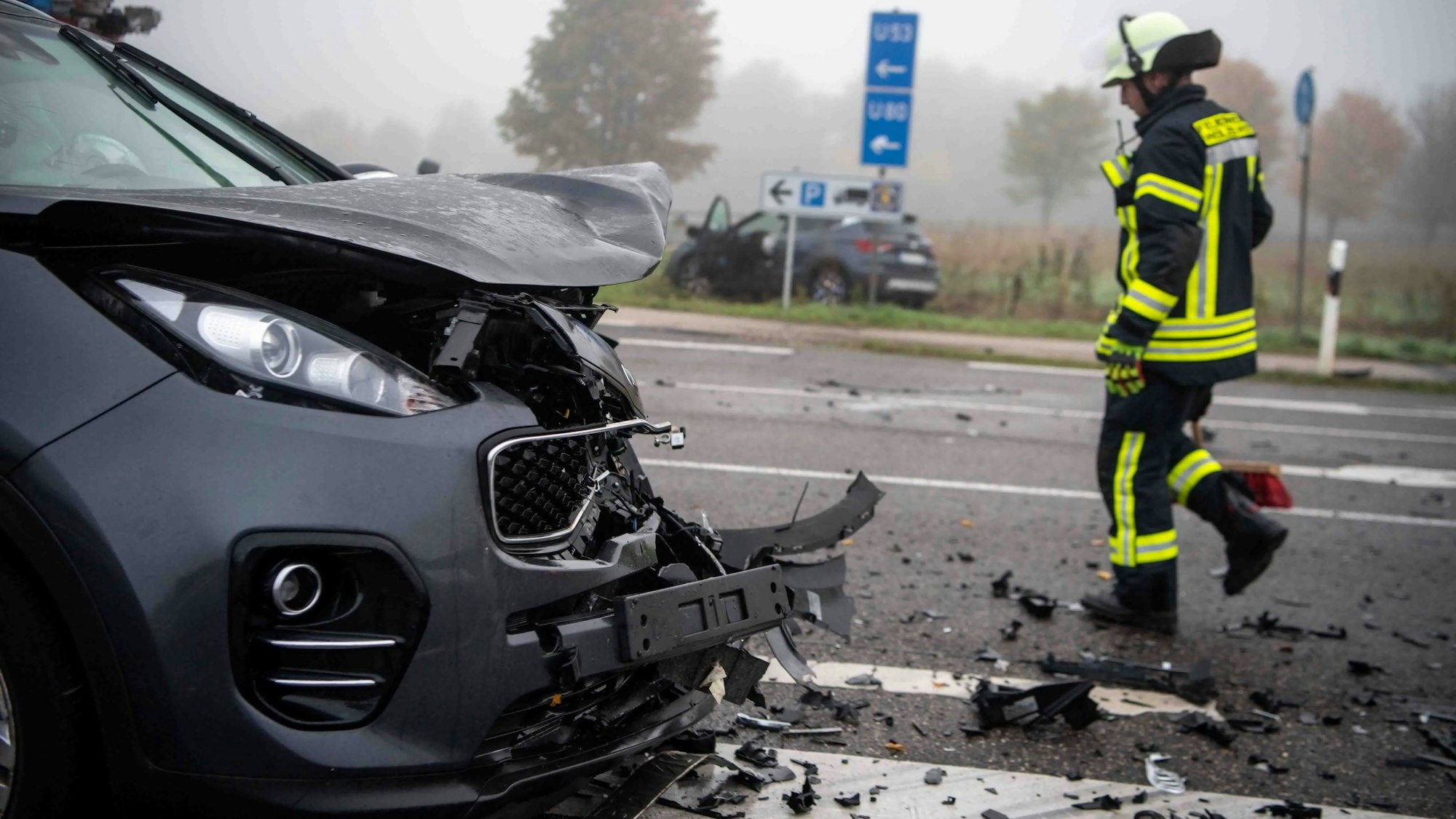 Ein Feuerwehrmann läuft nach einem Zusammenstoß zweier Autos über die mit Autoteilen übersäte Fahrbahn der L 163.