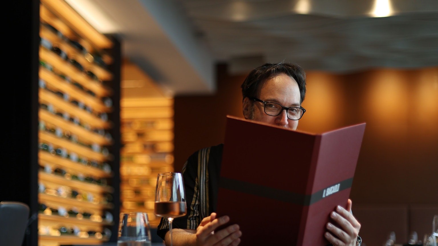 Mann mit Brille schaut in eine Speisekarte