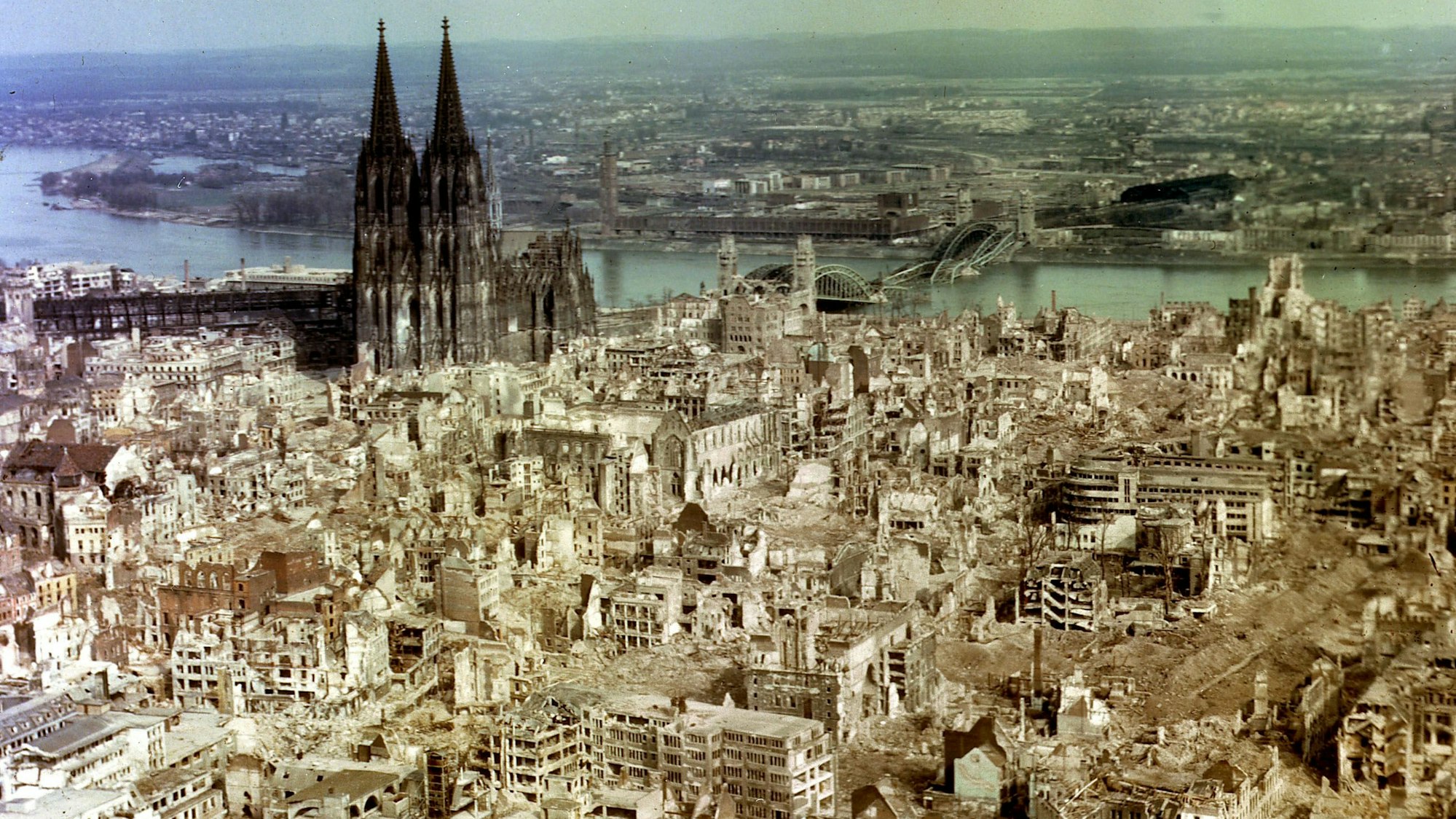 Die Luftaufnahme aus dem Jahr 1945 zeigt die im Zweiten Weltkrieg durch alliierte Bombenangriffe zerstörte Innenstadt von Köln, links der fast unbeschädigte Kölner Dom.