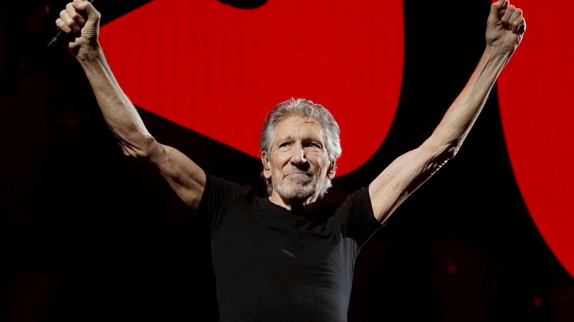 Roger Waters, Mitbegründer der Rockgruppe Pink Floyd, steht mit ausgebreiteten Armen auf einer Konzertbühne