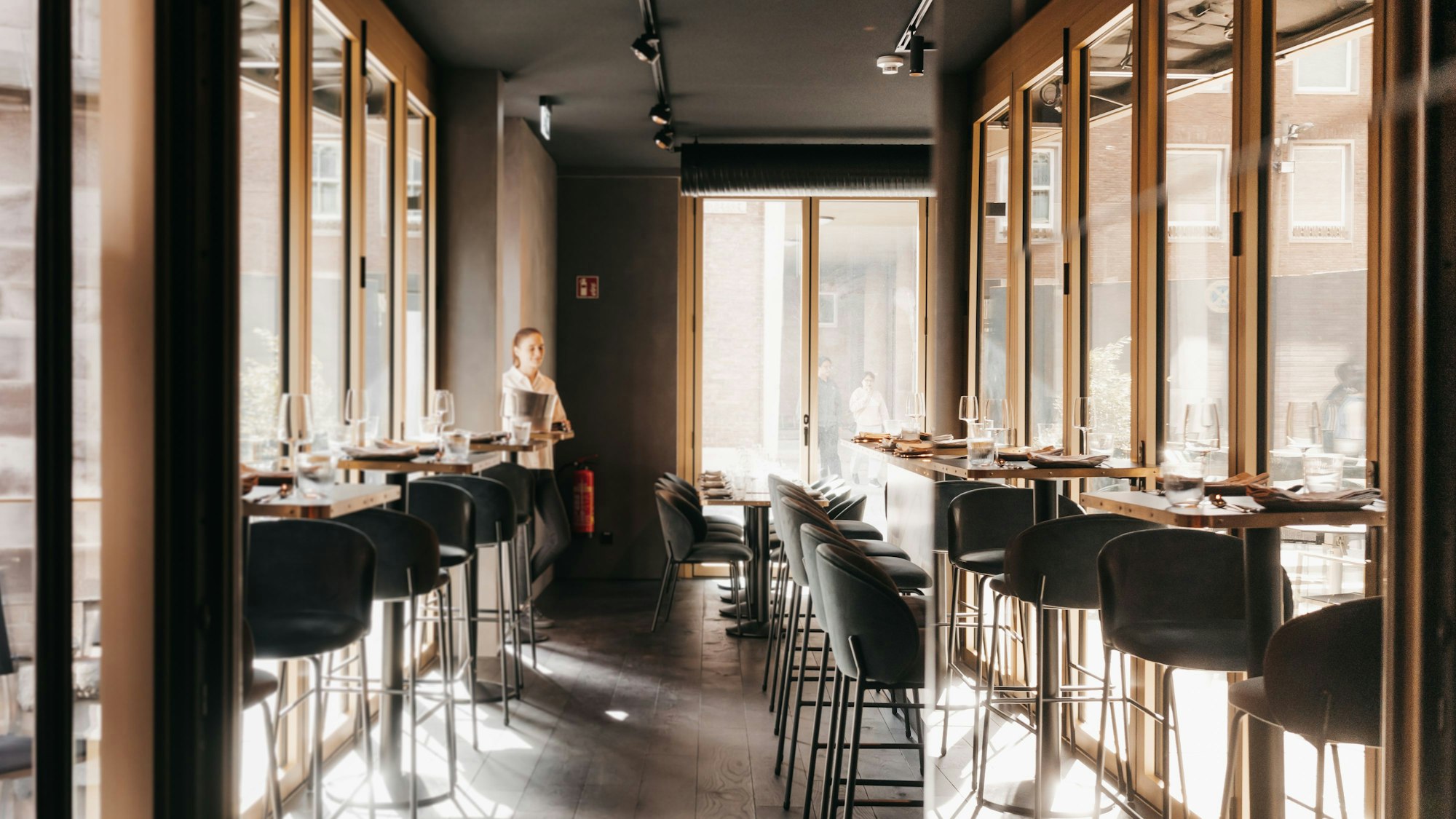 hohe Tische mit Barstühlen in einem hellen Raum