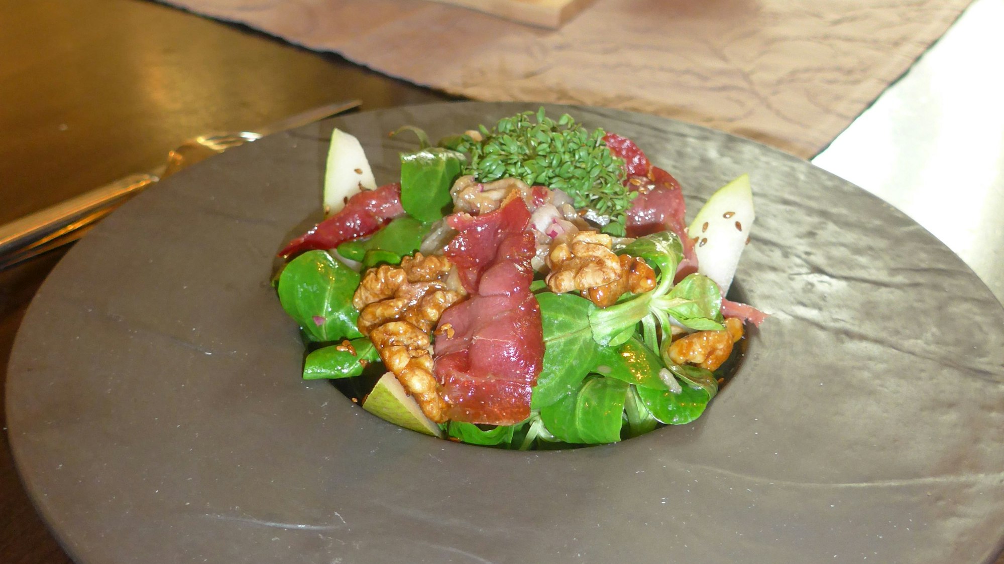 Die Vorspeise des Weihnachtsmenüs, zubereitet im Dezember 2022 im Haus Bosen in Erftstadt: Feldsalat mit krossem Serranoschinken, Birnen-Vinaigrette und Walnuss