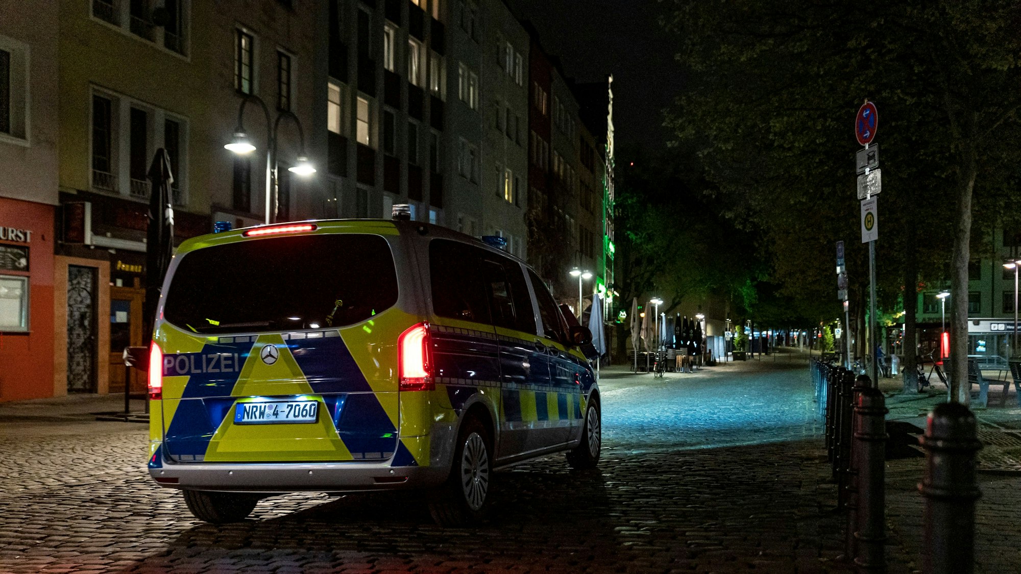 Ein Polizeibus steht auf einer Straße mit Kopfsteinpflaster bei Nacht.