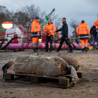 Auf einer Baustelle liegen zwei entschärfte Weltkriegsbomben, im Hintergrund sind Mitarbeitende des Kampfmittelräumdiensts zu sehen.