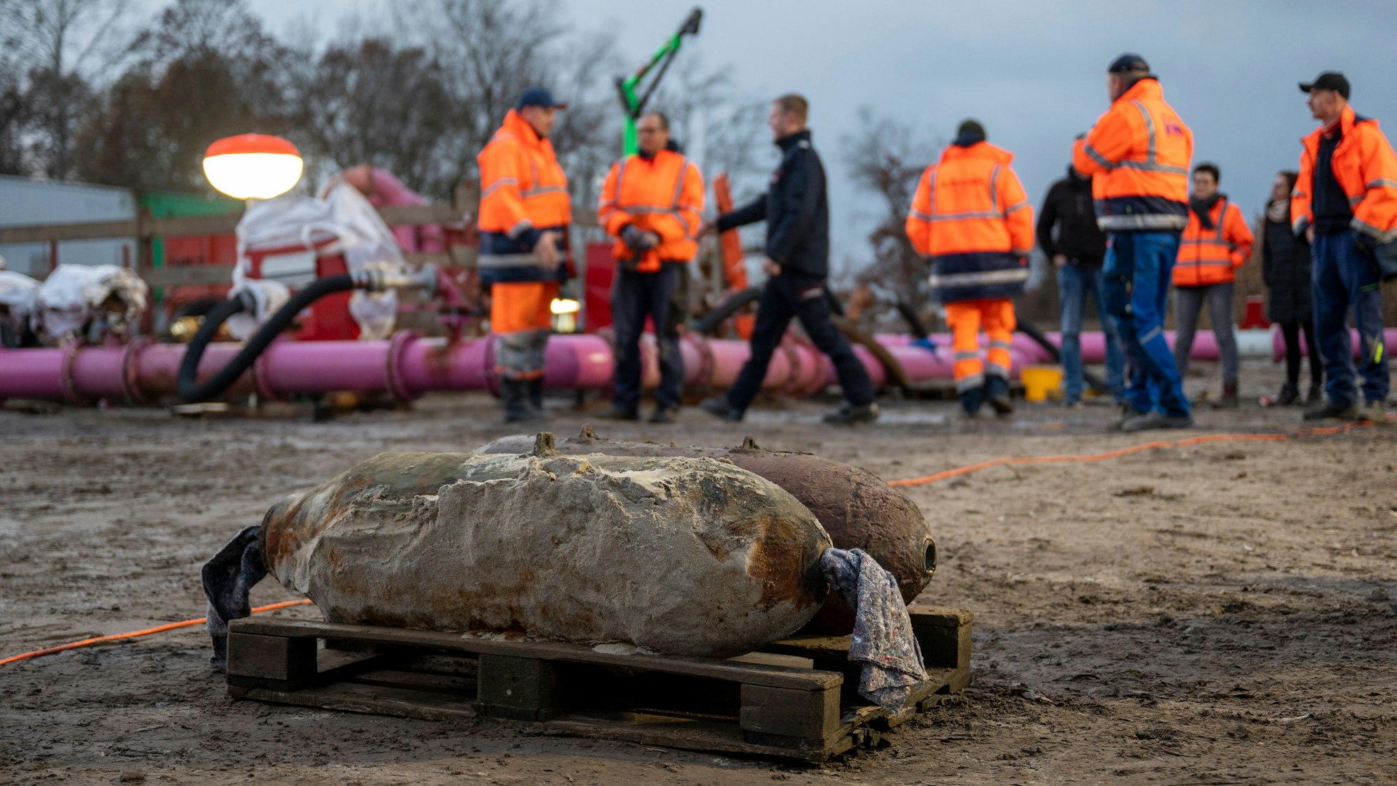 Auf einer Baustelle liegen zwei entschärfte Weltkriegsbomben, im Hintergrund sind Mitarbeitende des Kampfmittelräumdiensts zu sehen.