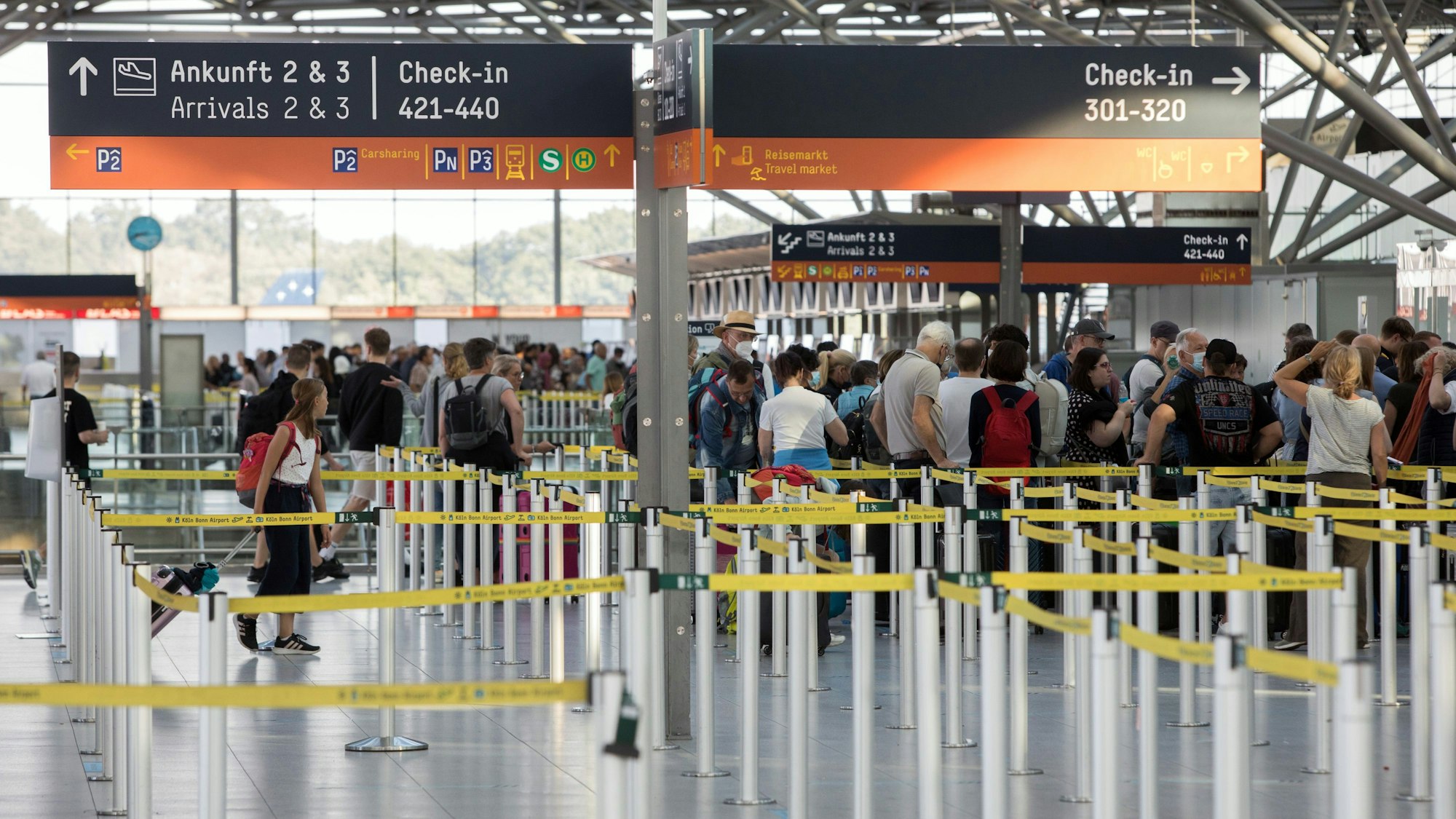Reisende stehen in einer Warteschlange vor dem Check-In-Schalter am Flughafen Köln/Bonn.