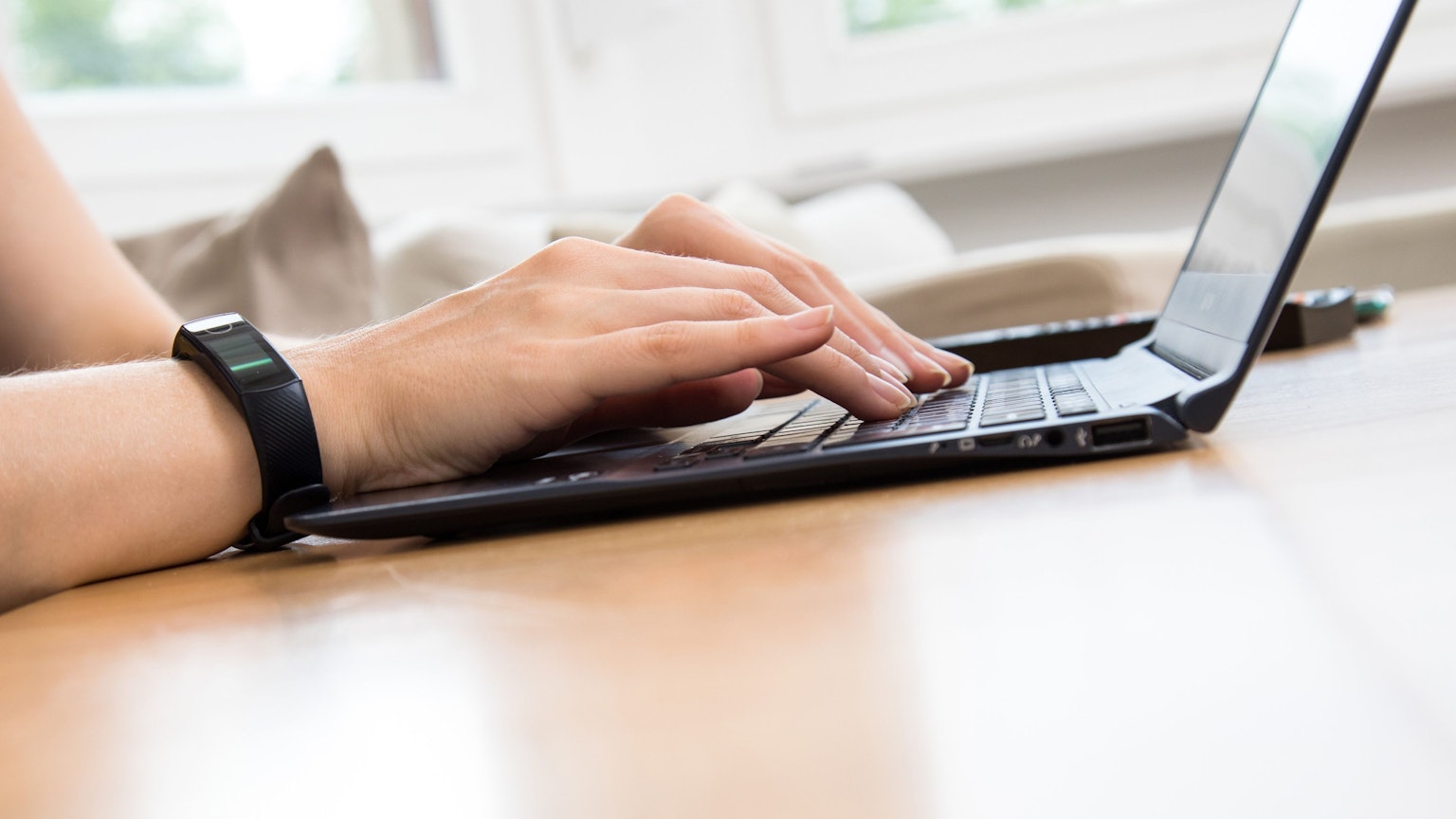 Eine Person tippt etwas in einen Laptop ein.