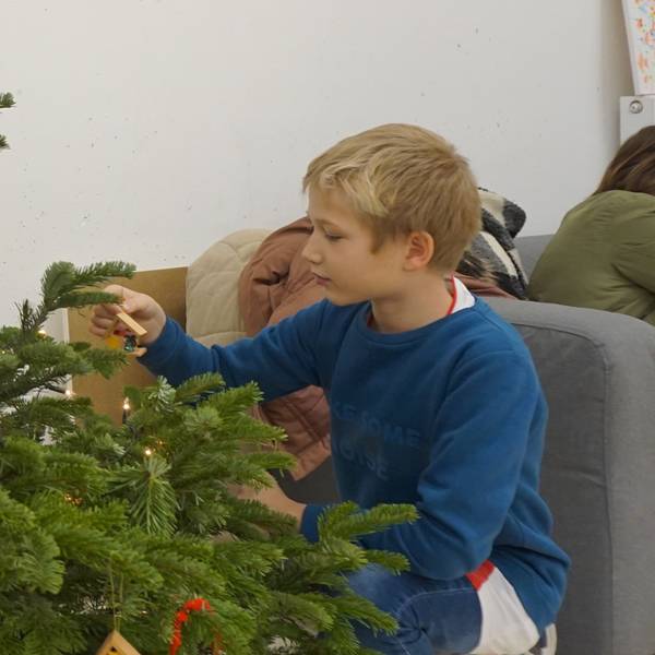 Ein Junge schmückt einen Weihnachtsbaum.