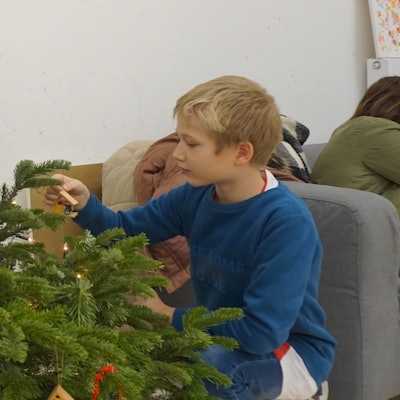 Ein Junge schmückt einen Weihnachtsbaum.