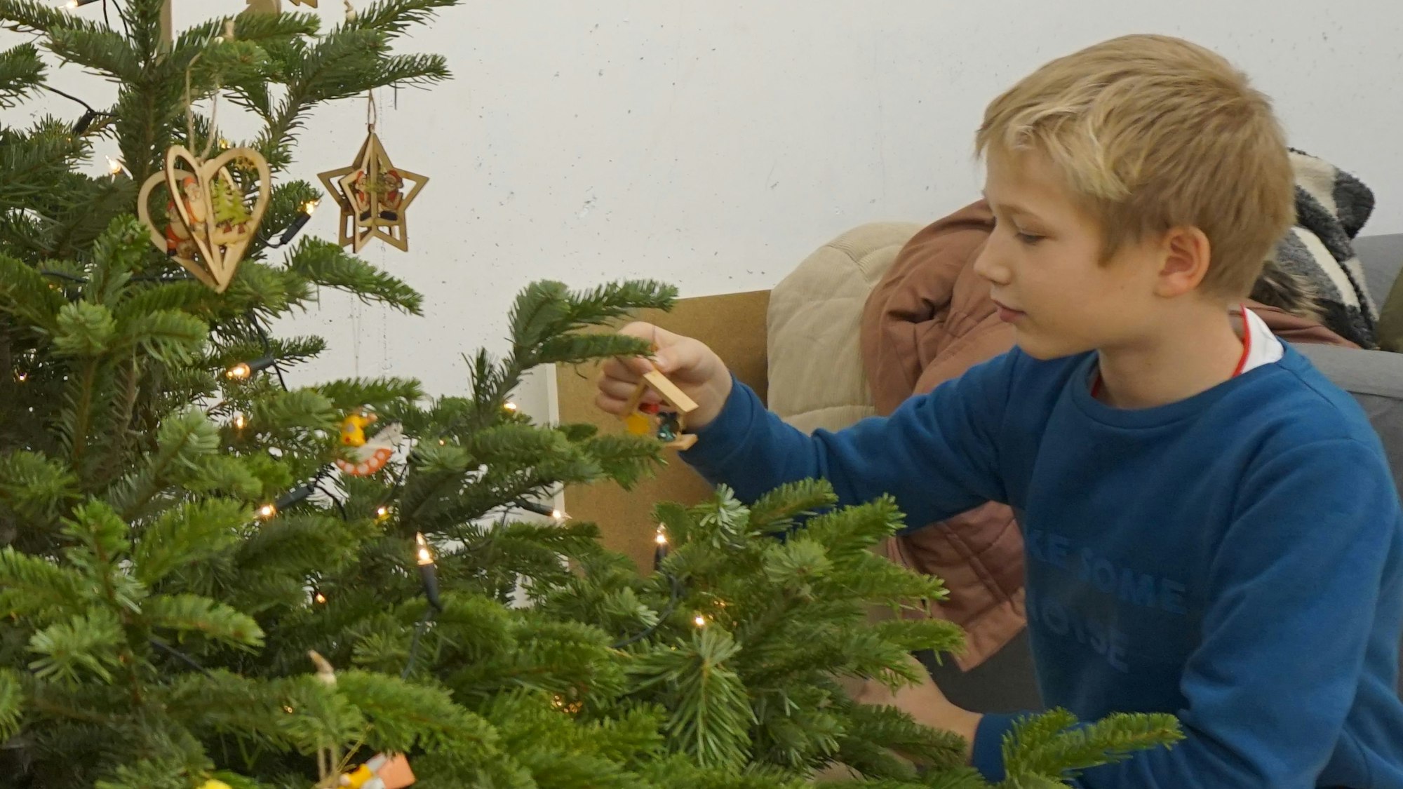 Ein Junge schmückt einen Weihnachtsbaum.