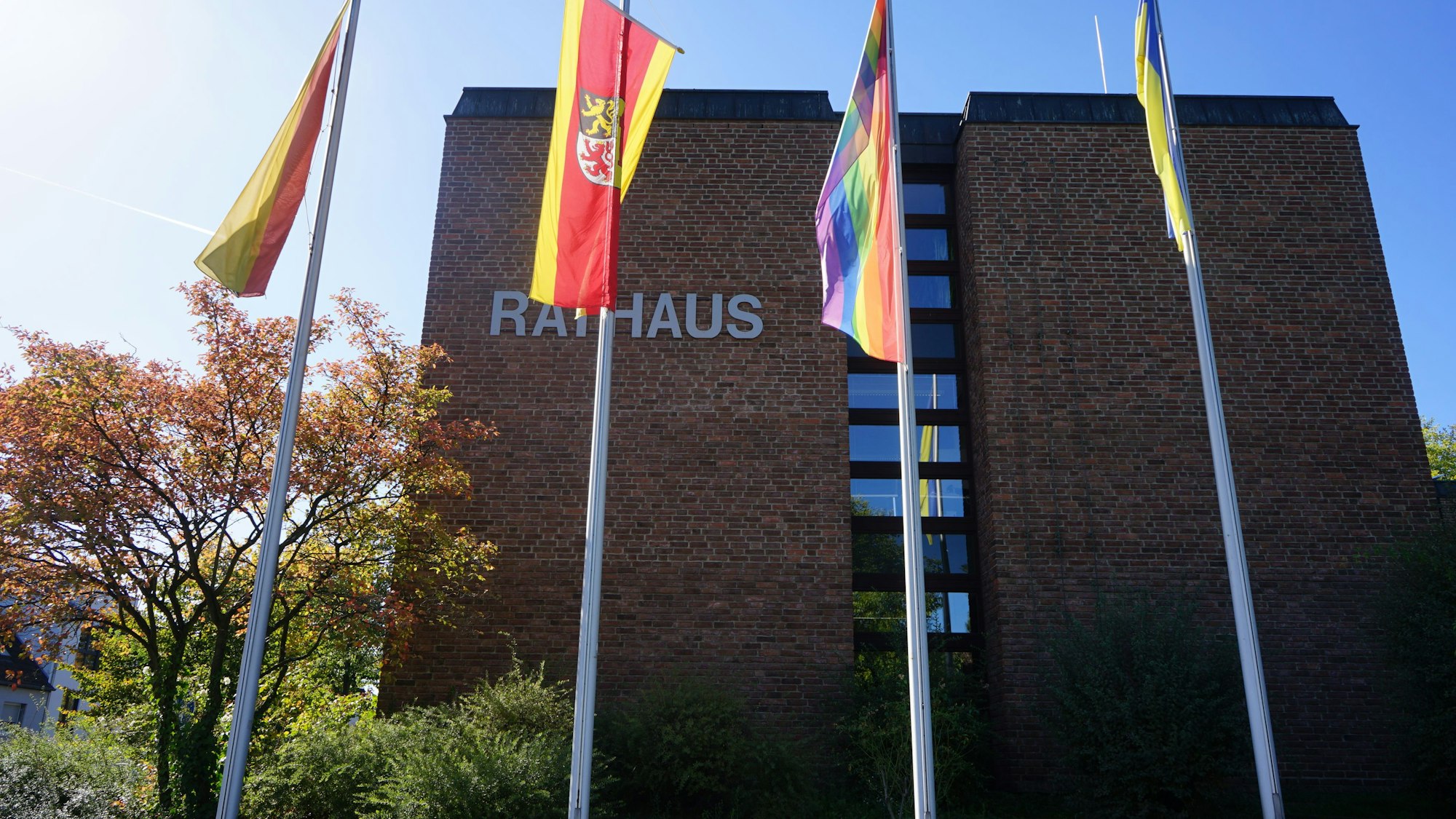 Vor dem Rathaus Kerpen, einem funktionalen Bau mit roten Ziegelsteinen, wehen Fahnen.