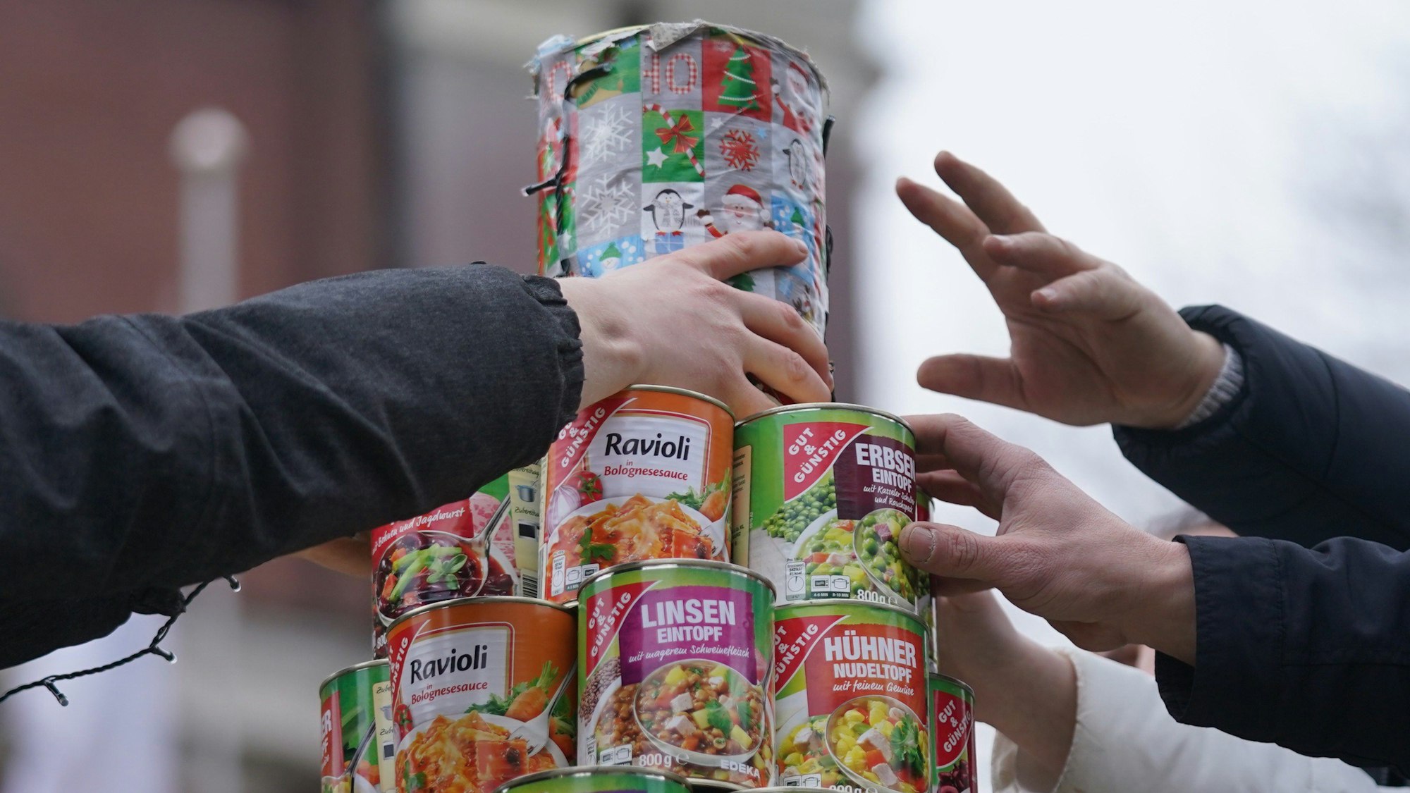 Helferinnen und Helfer stellen eine letzte Dose auf den größten Weihnachtsbaum aus Konservendosen auf dem Kirchplatz vor der Hamburger Hauptkirche Sankt Michaelis.