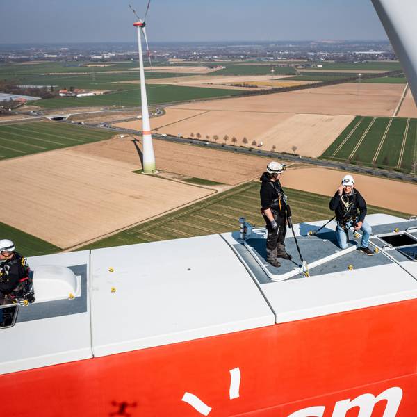 Personen stehen auf einem Windrad. In NRW soll die Abstandsregel für Windräder zu Siedlungen fallen. (Symbolbild)