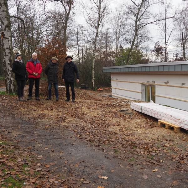 Silke Schäfer (v.l.), Jürgen Schreiber, Tobias Müller und Martin Schreiner stehen auf einem Waldweg. Neben ihnen ist ein Teil des Rohbaus des Vereinsheims.