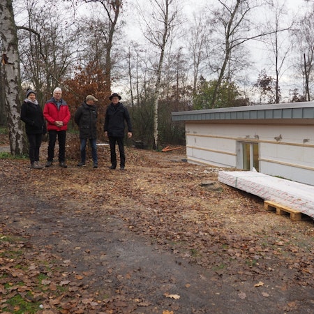 Silke Schäfer (v.l.), Jürgen Schreiber, Tobias Müller und Martin Schreiner stehen auf einem Waldweg. Neben ihnen ist ein Teil des Rohbaus des Vereinsheims.
