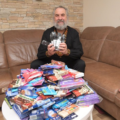 Paul sitzt auf dem Wohnzimmersofa und zeigt medizinische Armbinden und Süßigkeiten, die er mit in die Ukraine nimmt.