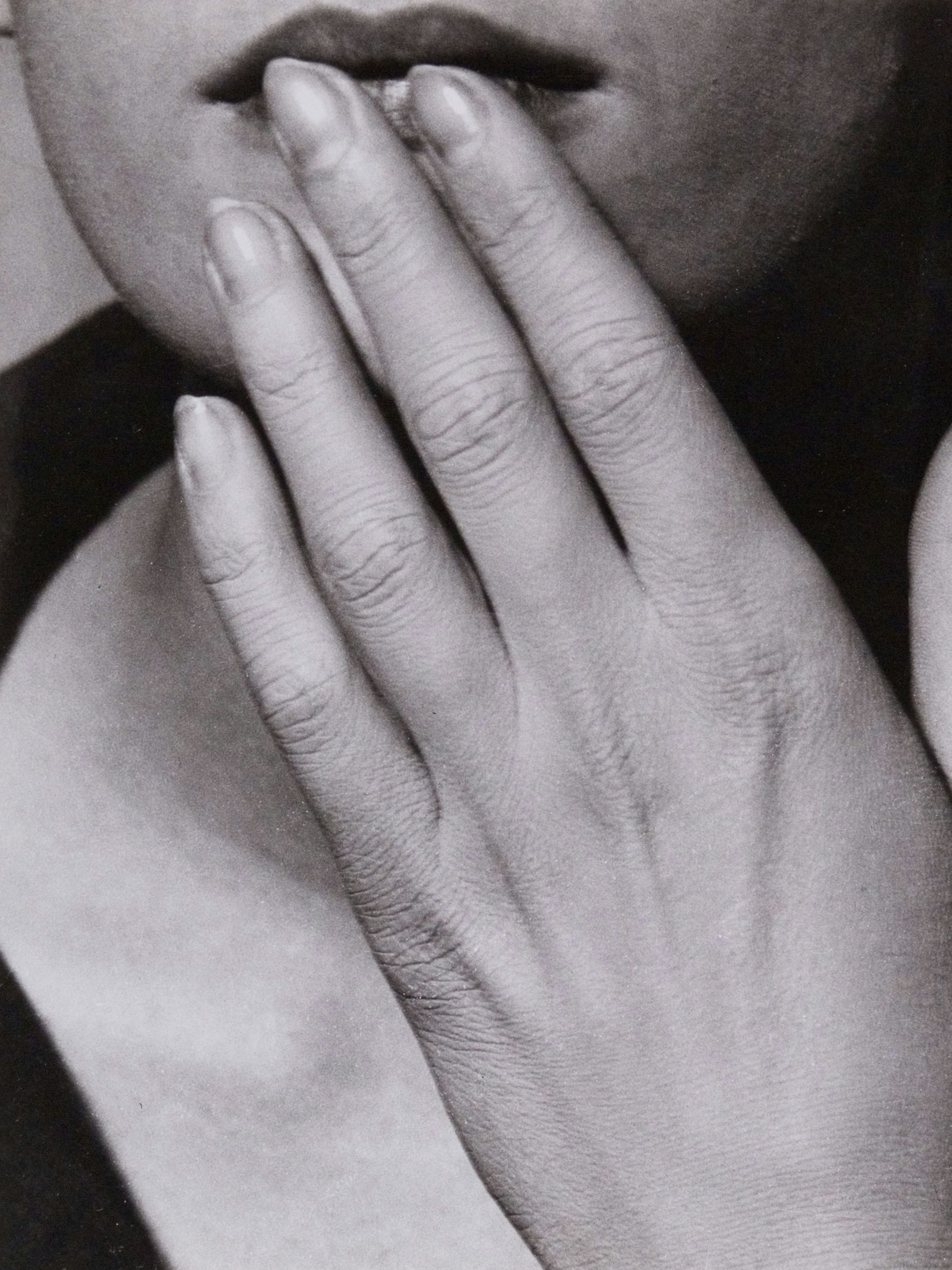 Man Rays Aufnahme „Hand auf den Lippen“ zeigt eine Frau, die sich die Hand an die Unterlippe hält.