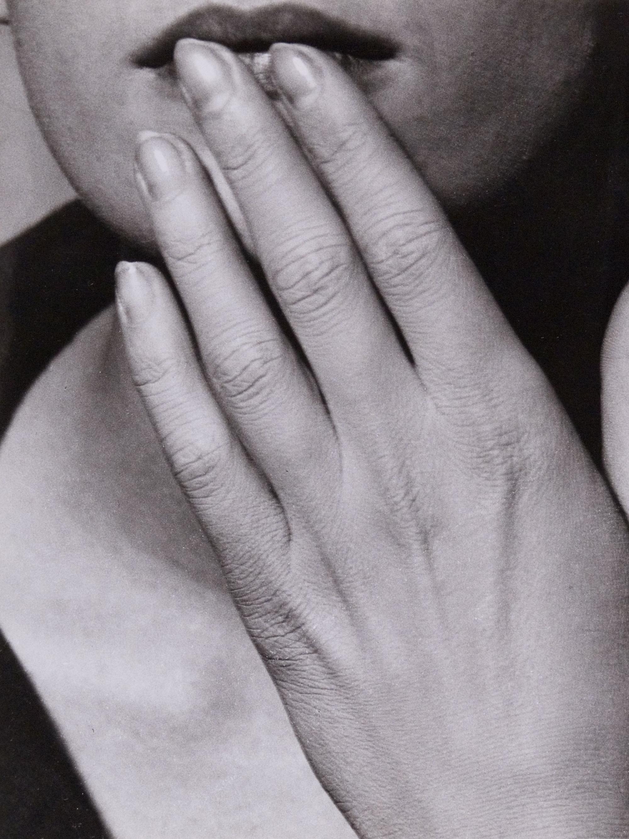 Man Rays Aufnahme „Hand auf den Lippen“ zeigt eine Frau, die sich die Hand an die Unterlippe hält.