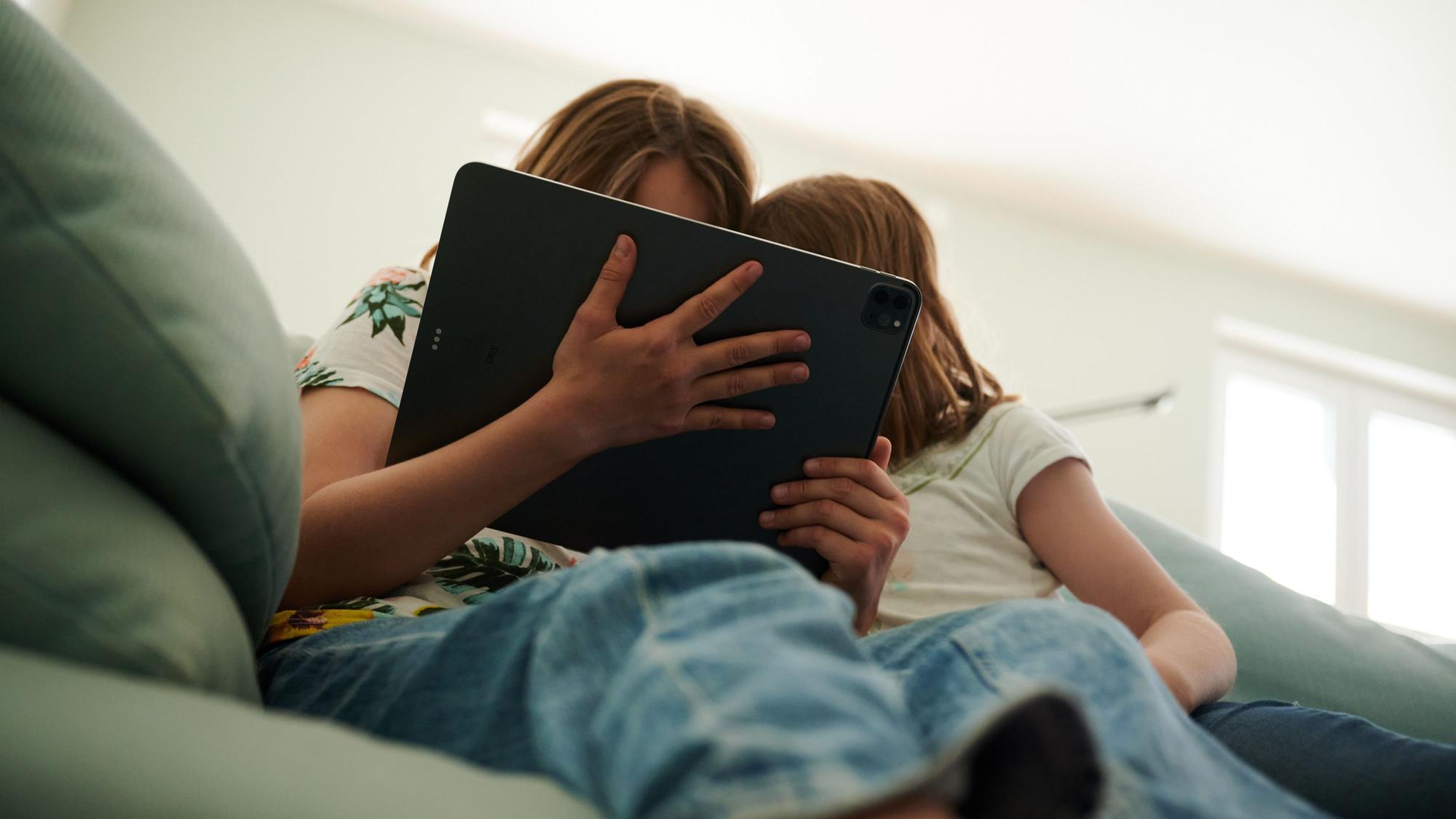 Lernen mit dem Tablet - im Saarland bald der Regelfall. Das Bild zeigt zwei Kinder, die auf dem Sofa sitzen und sich mit einem Tablet beschäftigen.